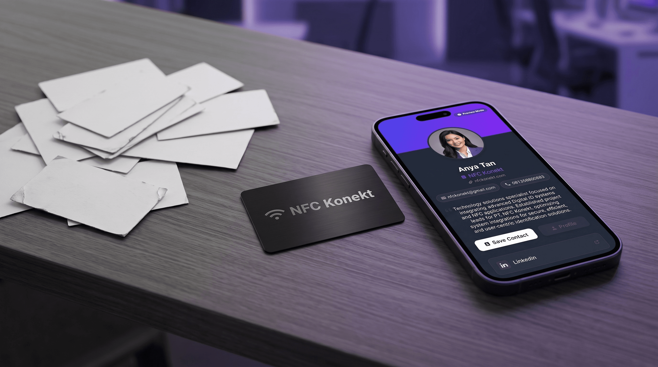 A pile of ordinary paper business cards beside a single NFC Konekt card and a phone displaying a full digital profile
